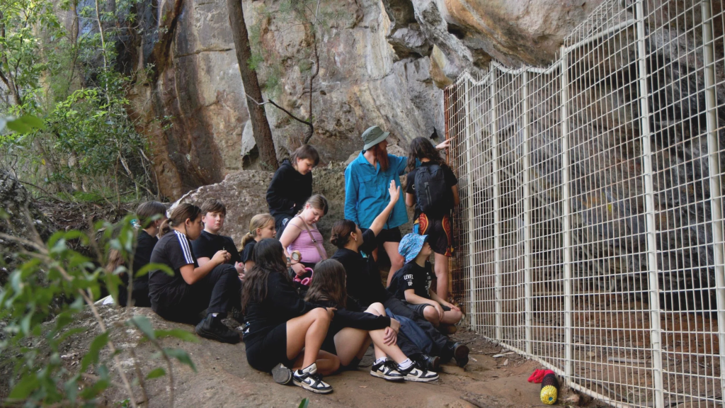 Youth on a cultural tour viewing protected rock art at a site with an Aboriginal-led organization